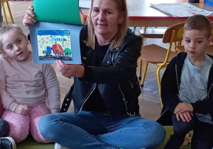Nauczyciel pokazuje dzieciom bajkowe ilustracje wykonane przez przedszkolaków