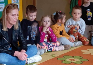 Dzieci słuchają jak nauczyciel czyta bajkę