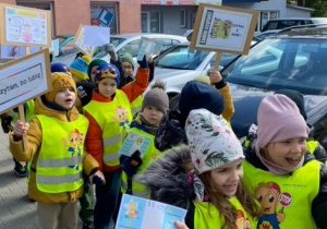 Dzieci idą z transparentami ulicami miasta