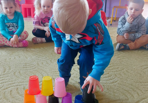 Chłopiec ustawia wieżę z kolorowych kubków