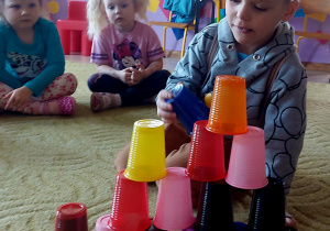 Chłopiec ustawia wieżę z kolorowych kubków