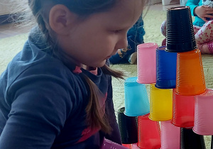 Dziewczynka ustawia wieżę z kolorowych kubków