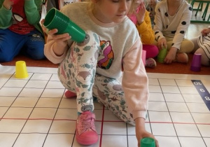 Dziewczynka ustawia plastikowe kubki na macie do kodowania