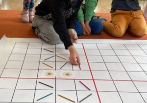 Chłopiec układa kolorowe patyczki na macie do kodowania