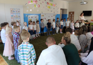 Dzieci i nauczycielka witają gości