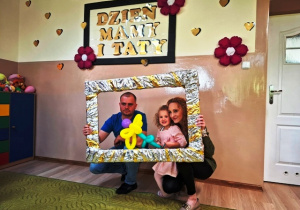 Dziewczynka z rodzicami pozuje do zdjęcia