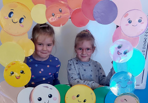 Dzieci pozują do zdjęcia w ramce z kolorowymi kropkami
