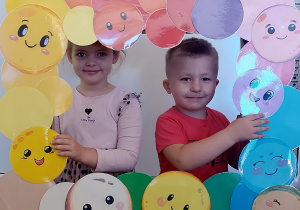 Dzieci pozują do zdjęcia w ramce z kolorowymi kropkami