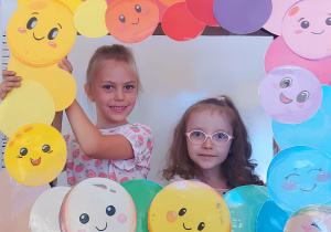 Dzieci pozują do zdjęcia w ramce z kolorowymi kropkami
