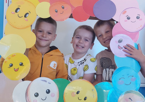Dzieci pozują do zdjęcia w ramce z kolorowymi kropkami