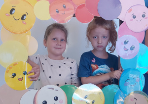 Dzieci pozują do zdjęcia w ramce z kolorowymi kropkami
