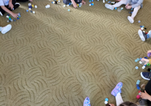 Dzieci układają plastikowe kropki na dywanie