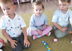 Dzieci układają plastikowe kropki na dywanie