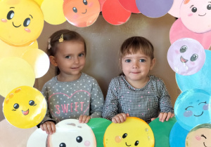 Dzieci pozują do zdjęcia w ramce z kolorowymi kropkami