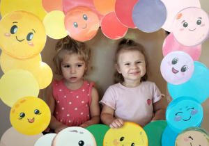 Dzieci pozują do zdjęcia w ramce z kolorowymi kropkami