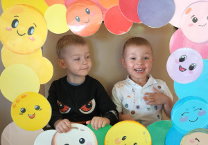 Dzieci pozują do zdjęcia w ramce z kolorowymi kropkami