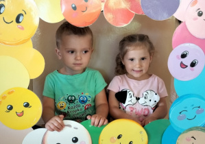 Dzieci pozują do zdjęcia w ramce z kolorowymi kropkami
