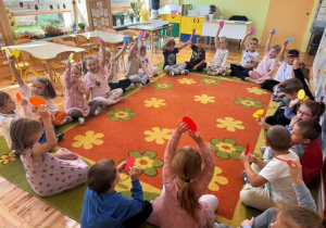 Dzieci podnoszą do góry kolorowe kropki