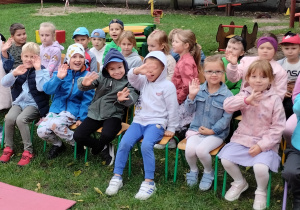 Dzieci siedzą na krzesełkach w ogrodzie przedszkolnym
