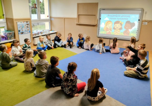 Dzieci siedzą w kole, śpiewają piosenkę