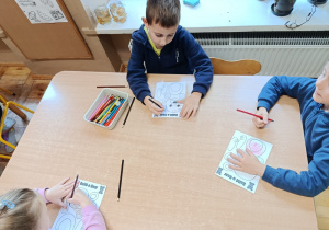 Dzieci na zajęciach z psychologiem kolorują misia