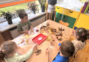 Dzieci przyklejają liście na słoiki