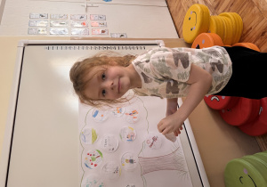 Chłopiec przykleja na szablon drzewa narysowany przez niego talent