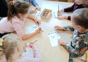 Dzieci na zajęciach z psychologiem kolorują misia