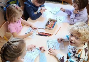 Dzieci na zajęciach z psychologiem kolorują misia