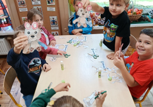 Dzieci na zajęciach z psychologiem kolorują misia