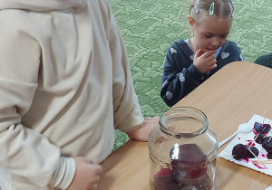 Dziewczynka wkłada plaster buraka do słoika