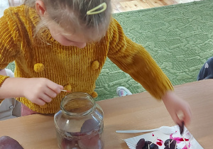 Dziewczynka wkłada plaster buraka do słoika