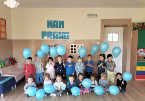 Dzieci pozują do zdjęcia trzymając błękitne balony