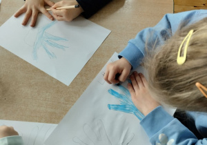 Dzieci kolorują kontur dłoni na niebiesko symbolizującą prawa dziecka
