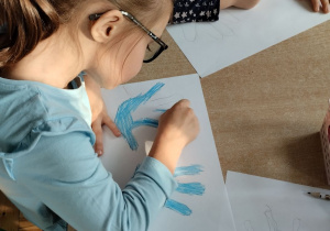 Dzieci kolorują kontur dłoni na niebiesko symbolizującą prawa dziecka