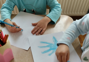 Dzieci kolorują kontur dłoni na niebiesko symbolizującą prawa dziecka