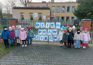 Dzieci pozują do zdjęcia przed przedszkolem