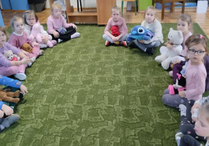 Dzieci siedzą na dywanie z misiami