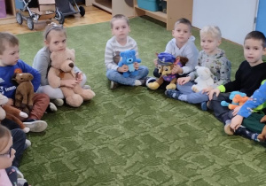 Dzieci siedzą na dywanie z misiami