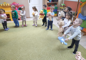 Dzieci stoją na dywanie z misiami