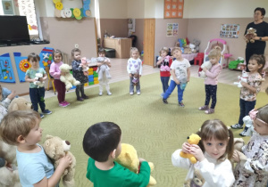 Dzieci stoją na dywanie z misiami