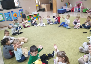 Dzieci siedzą na dywanie z misiami