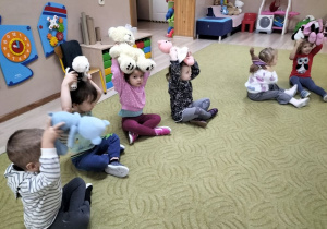 Dzieci siedzą na dywanie z misiami