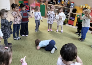 Dzieci stoją na dywanie w kole