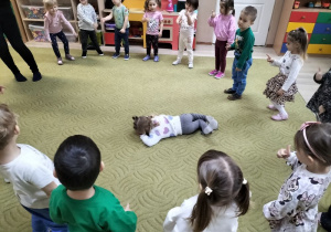 Dzieci stoją na dywanie w kole