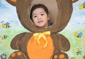 Dziecko pozuje do zdjęcia w ramce z misiem