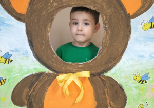 Dziecko pozuje do zdjęcia w ramce z misiem