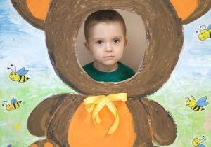 Dziecko pozuje do zdjęcia w ramce z misiem