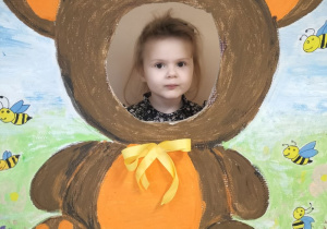 Dziecko pozuje do zdjęcia w ramce z misiem