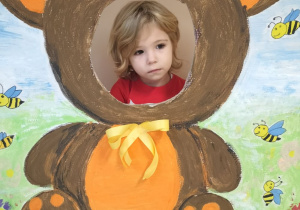 Dziecko pozuje do zdjęcia w ramce z misiem